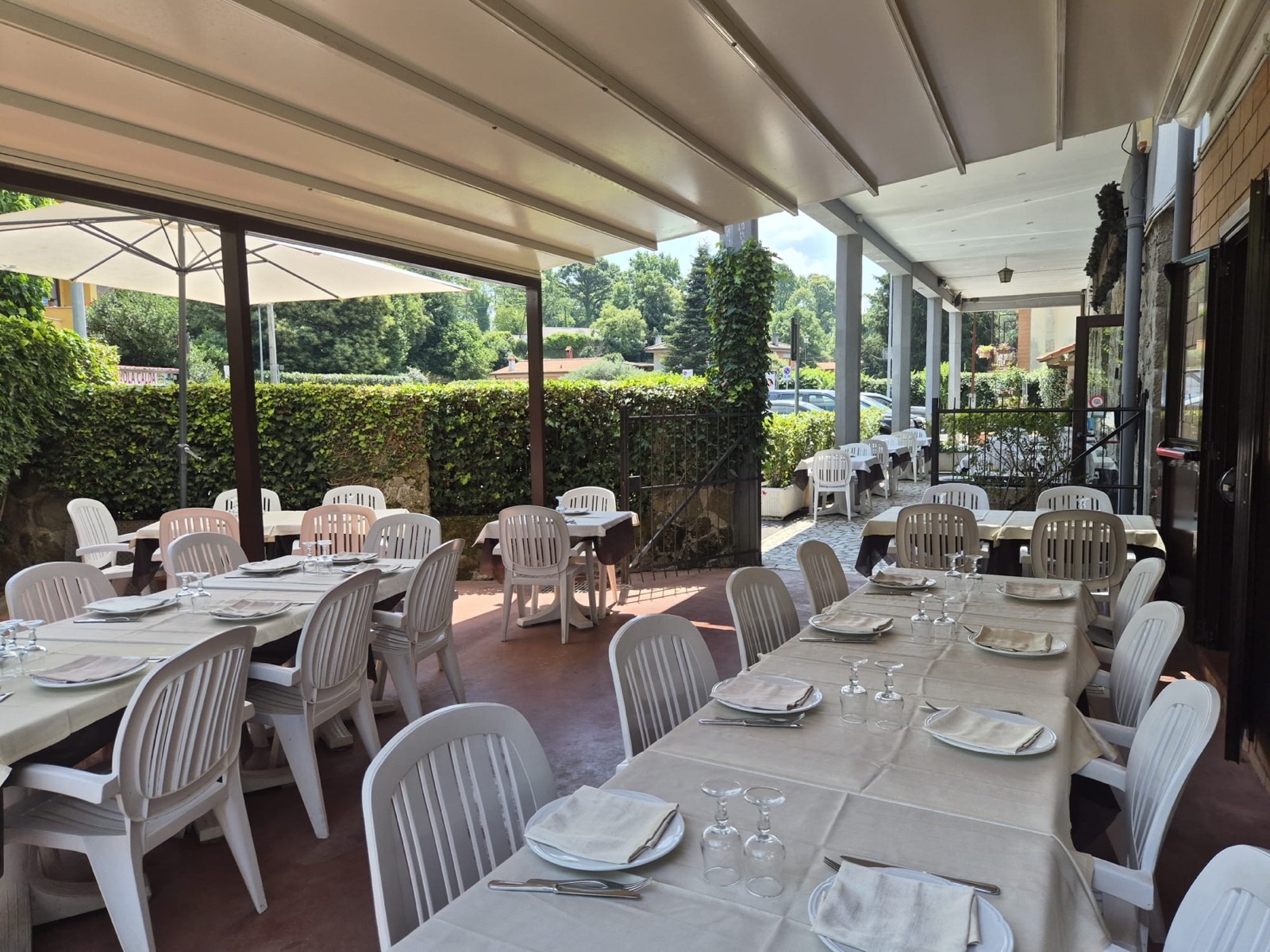Veranda coperta di Le Colombe affacciata sul giardino, tavoli apparecchiati